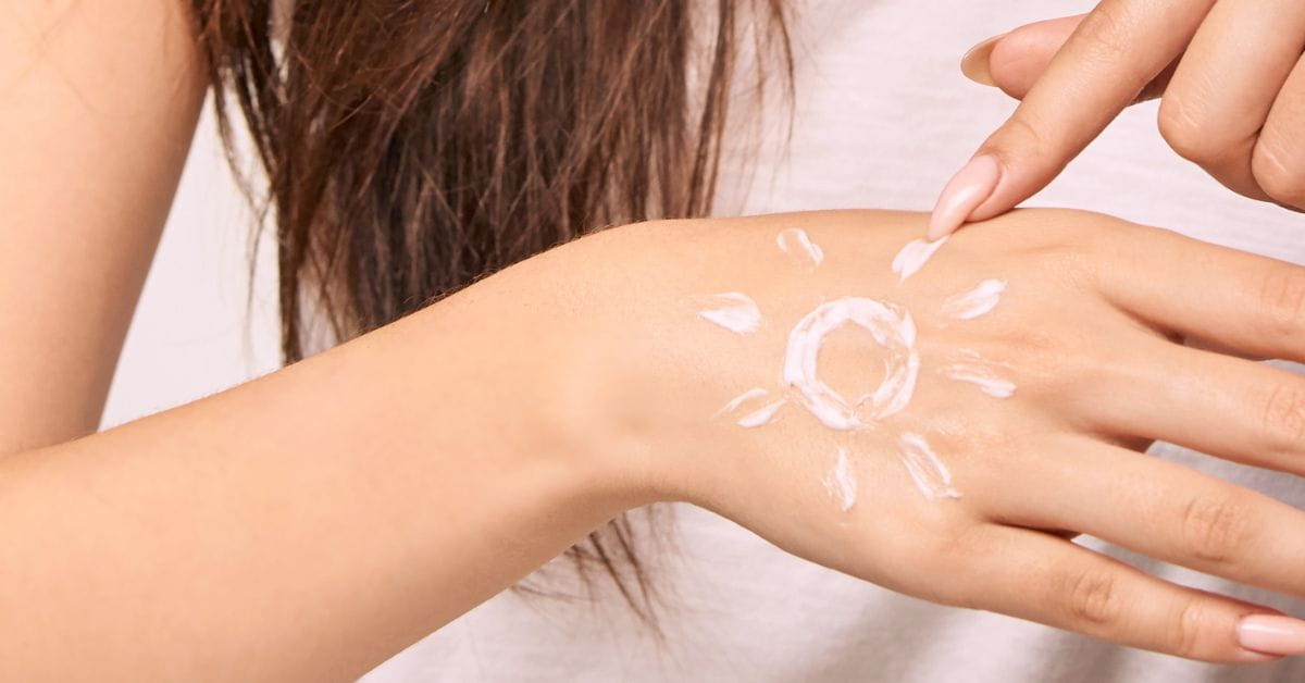 women applying sunscreen on her hand in the shape of a sun