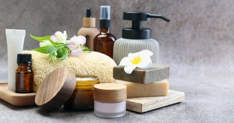 Different Body Care Products and Flowers on Grey Table for your Summer Body Care Routine: 15 Simple Ways to Care for Your Skin and Hair