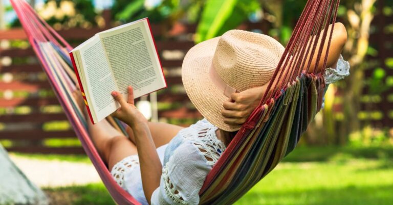Woman sitting in a hammock reading a book and drink coffee as a summer self-care routine